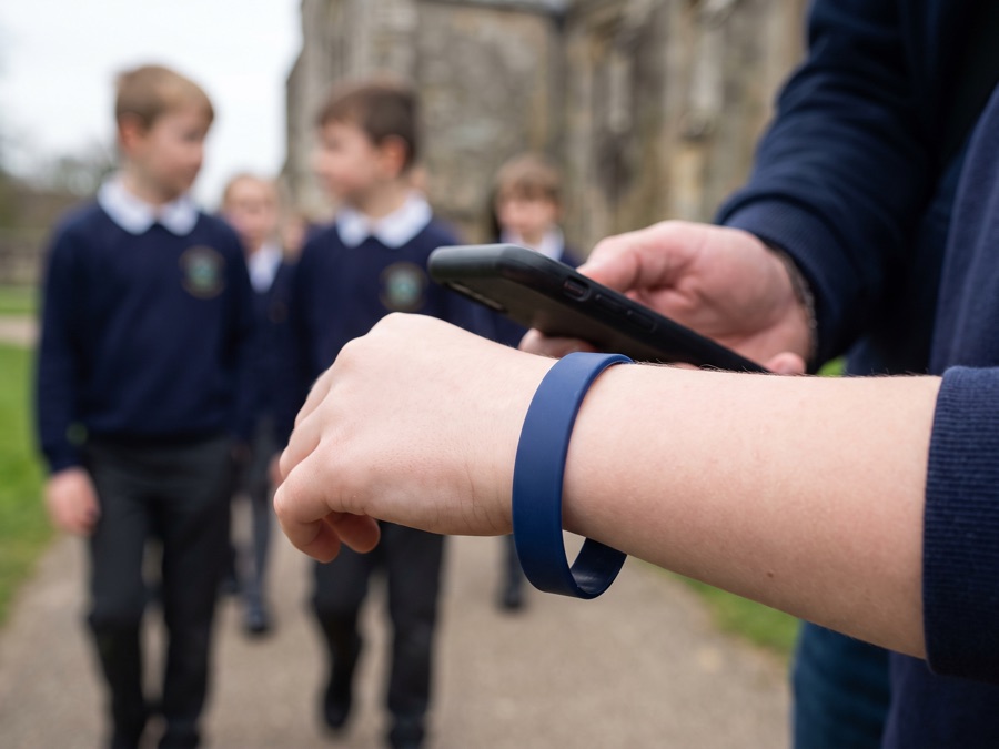 A child's wristband being scanned by a teacher on a school trip